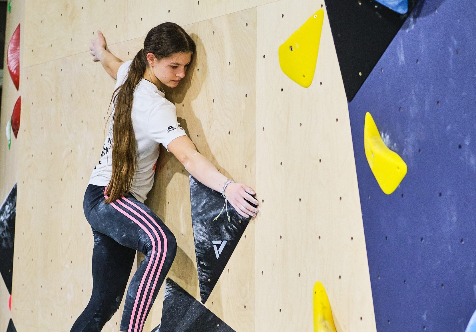 Djevojka se penje po stijeni u boulder dvorani