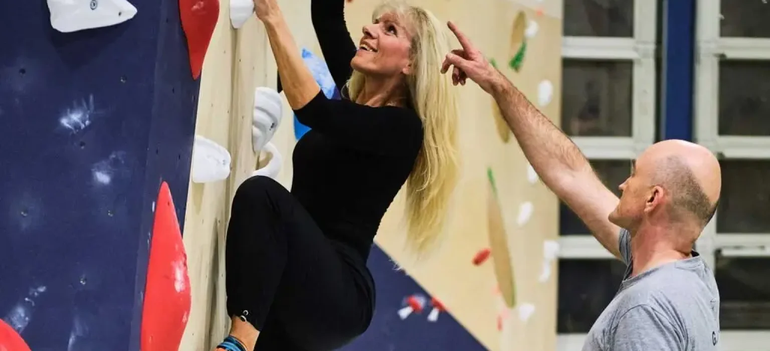 Penjačica na boulder stijeni uz usmjeravanje muškarca