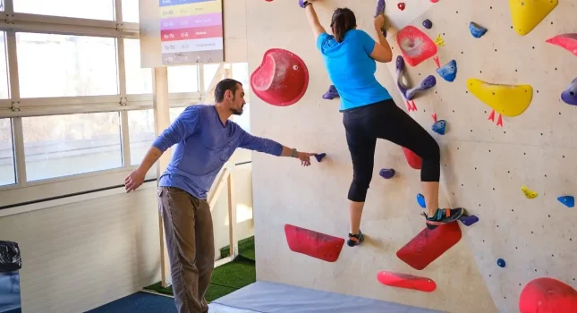 Instruktor pomaže penjačici na boulder stijeni
